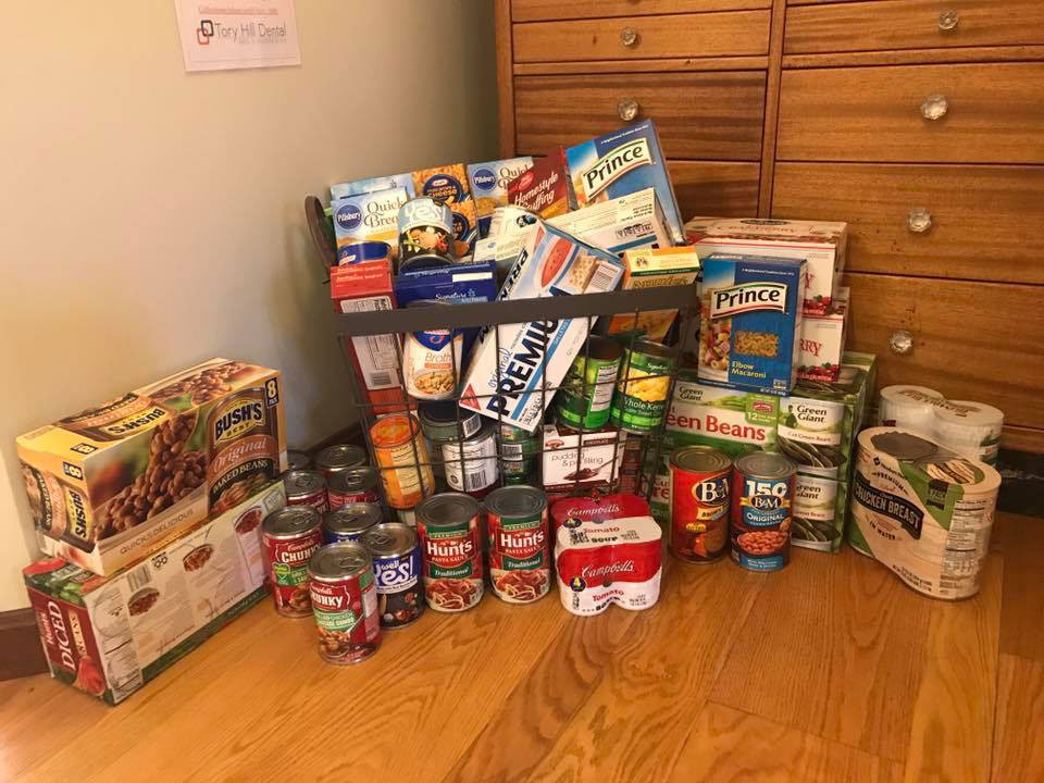 The image shows a collection of food items displayed on a surface, including canned goods, snacks, and other packaged products.