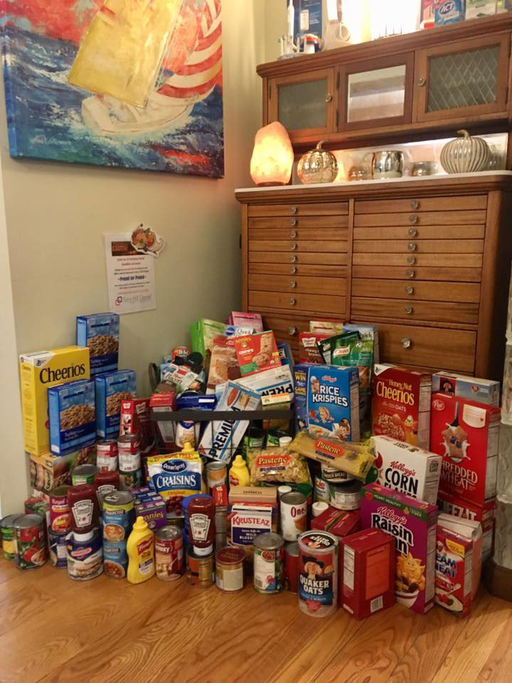 The image shows a collection of various food items displayed on a table, with a variety of packaged goods and cereals visible.