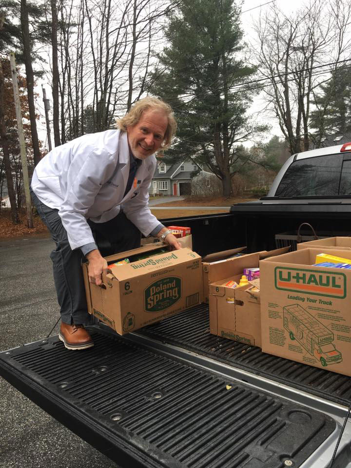 A man leaning over a flatbed truck filled with cardboard boxes containing various items, likely for donation or delivery.