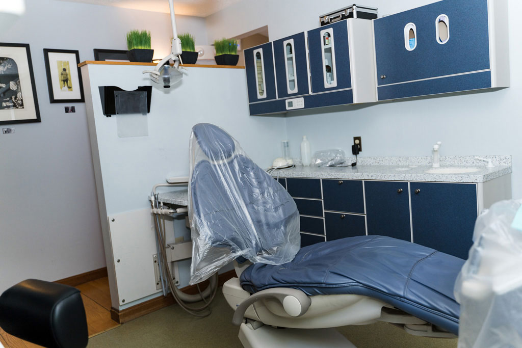 The image shows a dental office interior with a dentist's chair, sink, and other equipment, all in a modern design style.