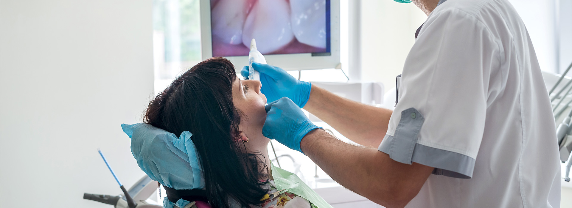 The image depicts a dental professional performing a procedure on a patient using dental instruments.