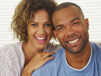 A man and a woman are smiling at the camera  the man has short hair and a beard, while the woman has long hair. They appear to be posing for a portrait.